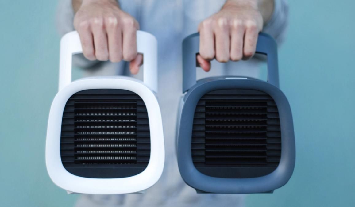 Two hands holding white and gray portable air coolers