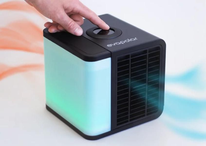 Hand adjusting a compact black air cooler with color-changing light